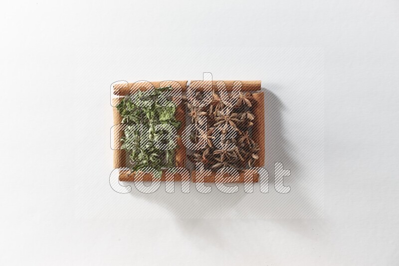 2 squares of cinnamon sticks full of star anise and dried mint leaves on white flooring