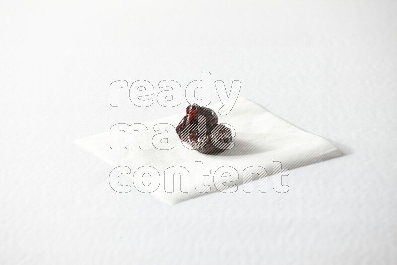 Two dried plums on a piece of paper on a white background in different angles