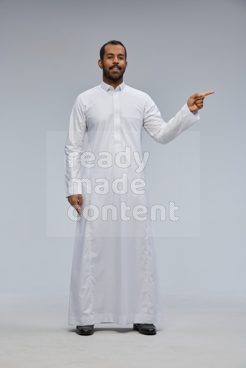 Saudi man Wearing Thob standing interacting with the camera on Gray background