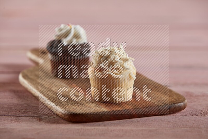 Vanilla mini cupcake topped with coconut on a wooden board