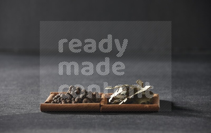 2 squares of cinnamon sticks full of allspice and bay laurel leaves on black flooring