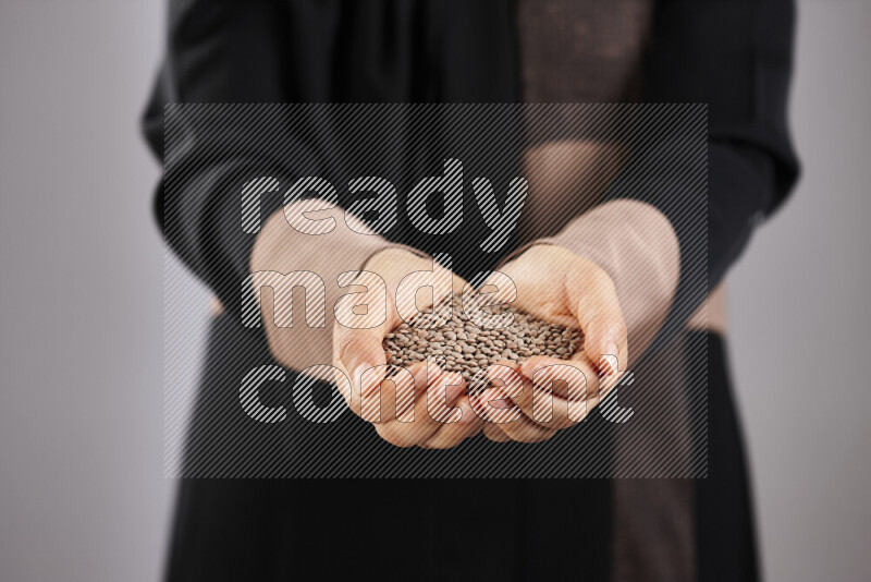 Woman in abaya holding different kinds of legumes in different positions