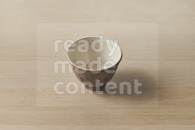 A decorative pottery bowl on light wooden background