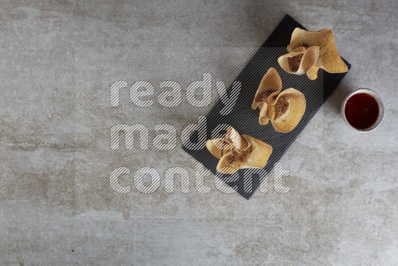 wonton cups with soy sauce ramkin on rectangle slate on grey textured counter top