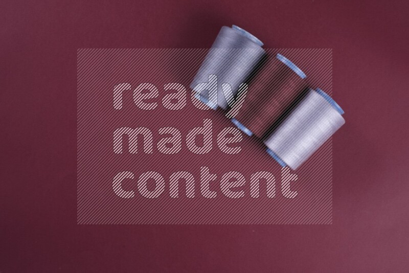 A grey collection of sewing and tailoring tools arranged on a red background