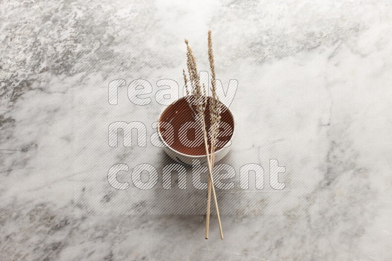 Wheat stalks on brown pottery bowl on grey marble background