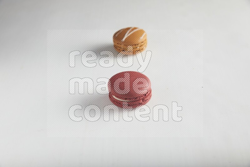 45º Shot of of two assorted Brown Irish Cream, and Red Velvet macarons on white background