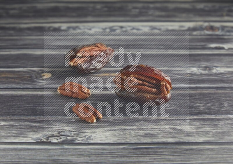 two pecan stuffed madjoul date on a wooden grey background