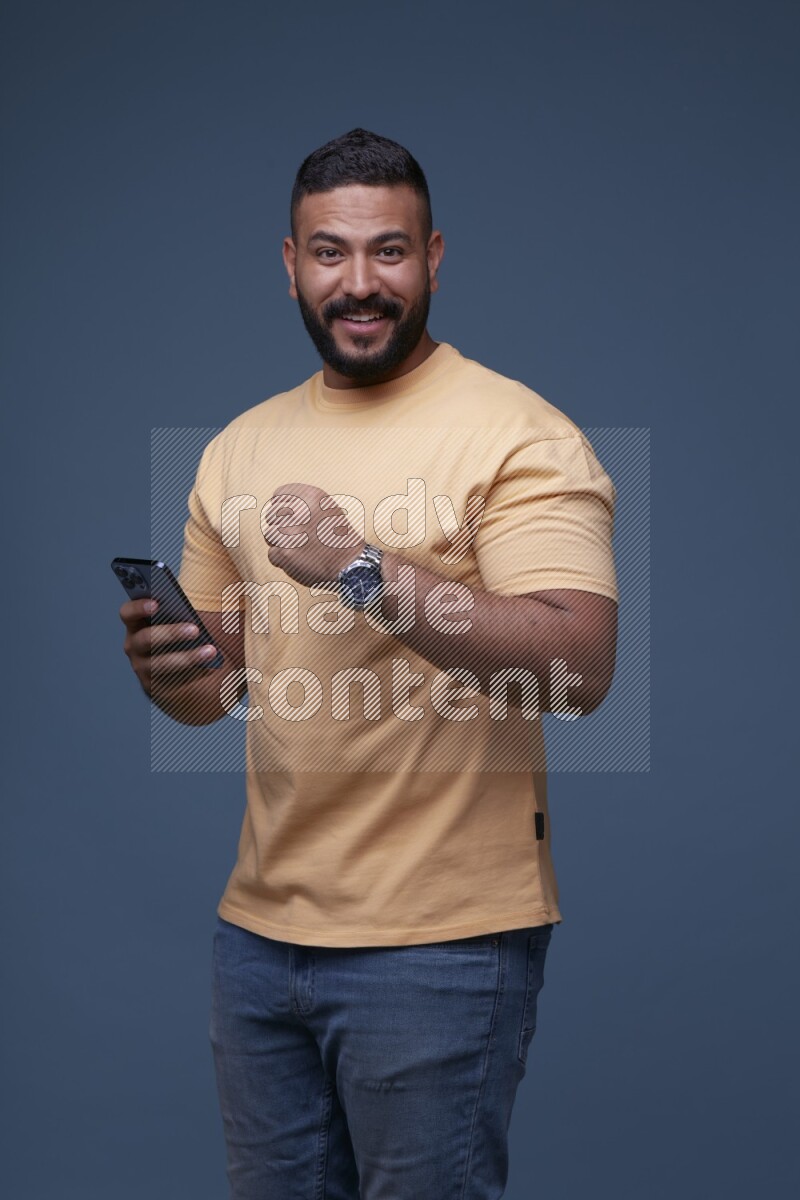 A man Texting on his phone on Blue Background wearing Orange T-shirt