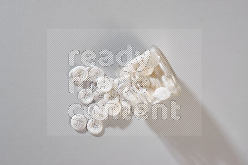 Colored buttons in a glass jar on grey background