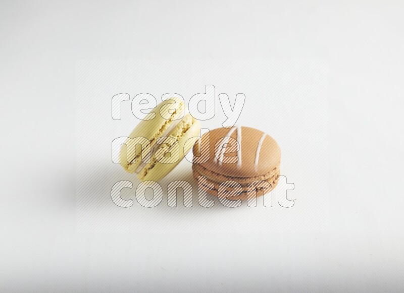 45º Shot of of two assorted Brown Irish Cream, and Yellow Lime macarons on white background