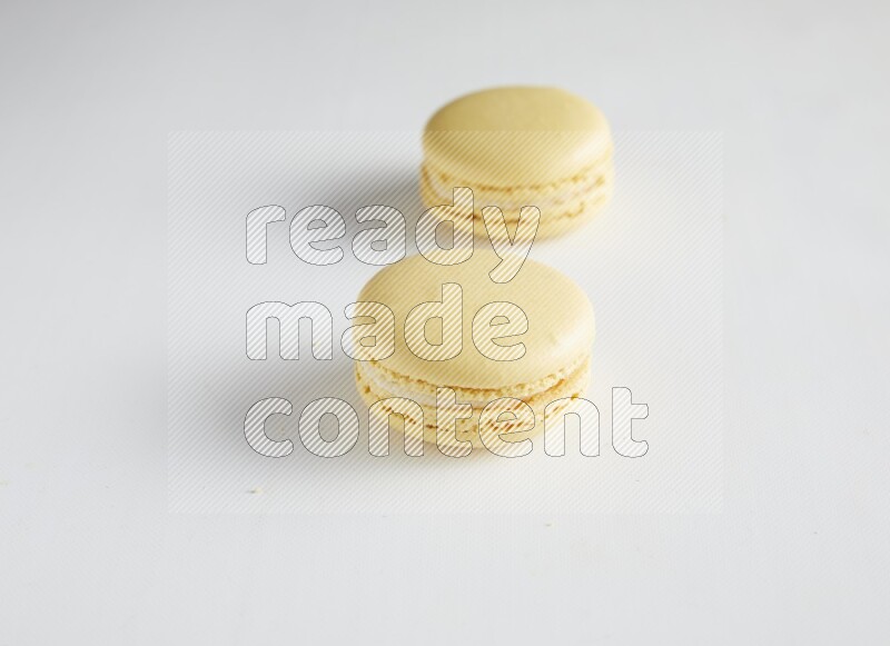 45º Shot of two Yellow Vanilla macarons on white background