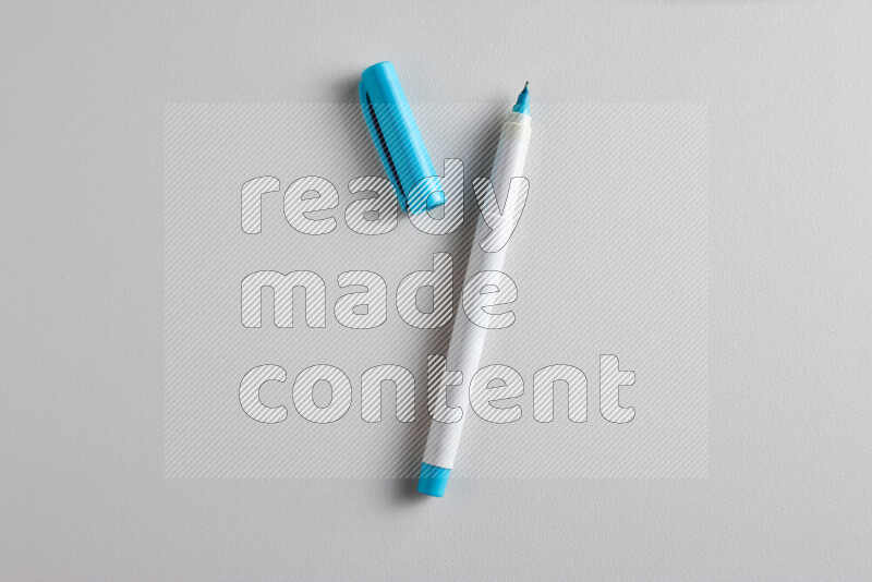 A close-up showing an open single coloring pen with a cap on grey background