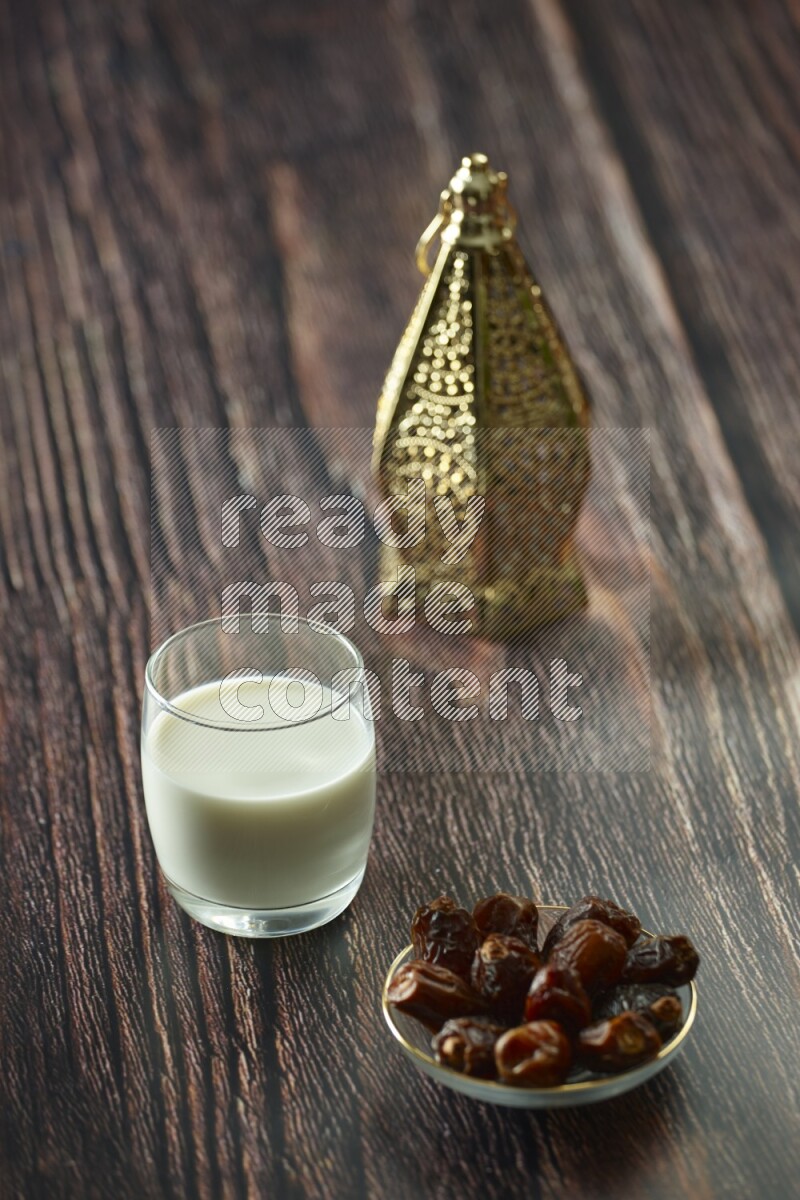 A golden lantern with different drinks, dates, nuts, prayer beads and quran on brown wooden background