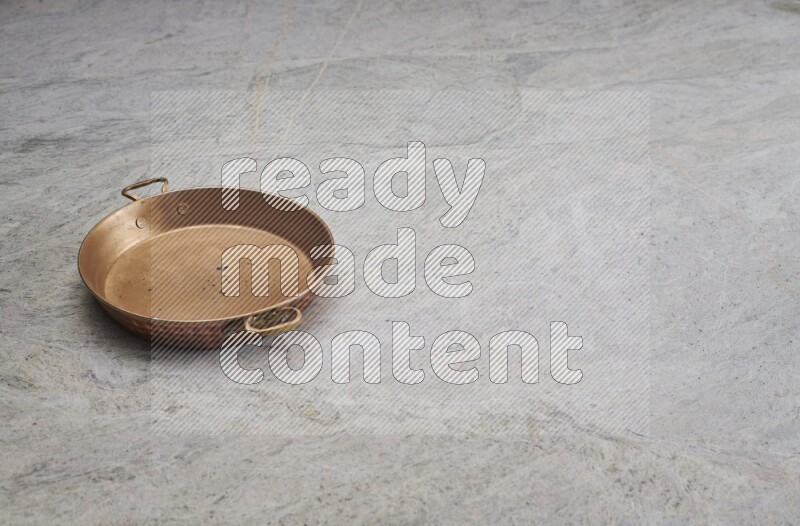 A small copper pan on grey marble background