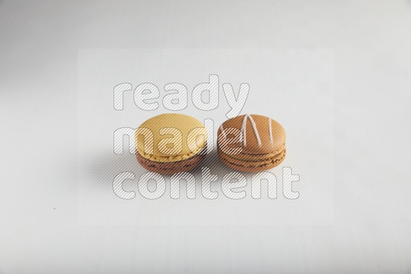 45º Shot of of two assorted Brown Irish Cream, and Yellow, and Brown Chai Latte macarons on white background
