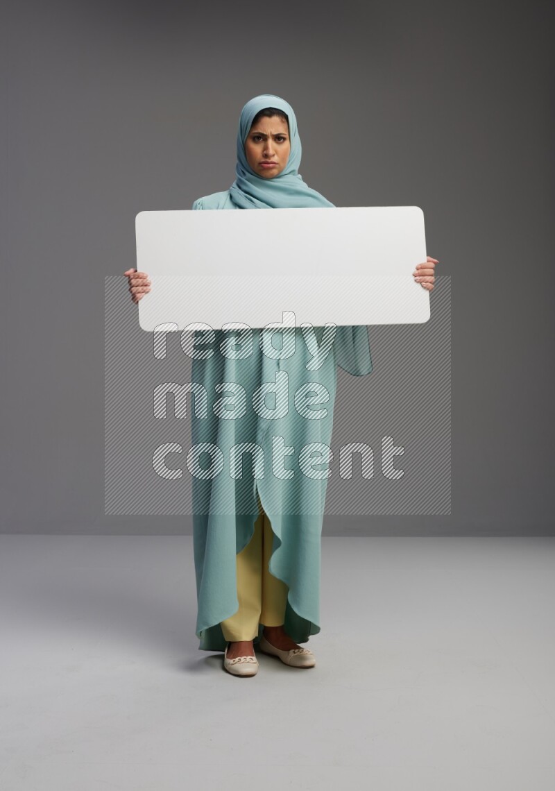 Saudi Woman wearing Abaya standing holding board on Gray background
