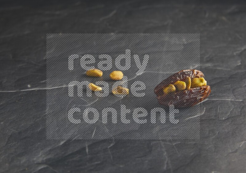 pistachios stuffed madjoul date on a black textured background