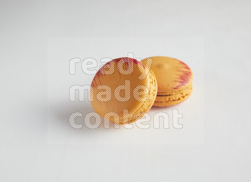 45º Shot of two orange Exotic macarons on white background
