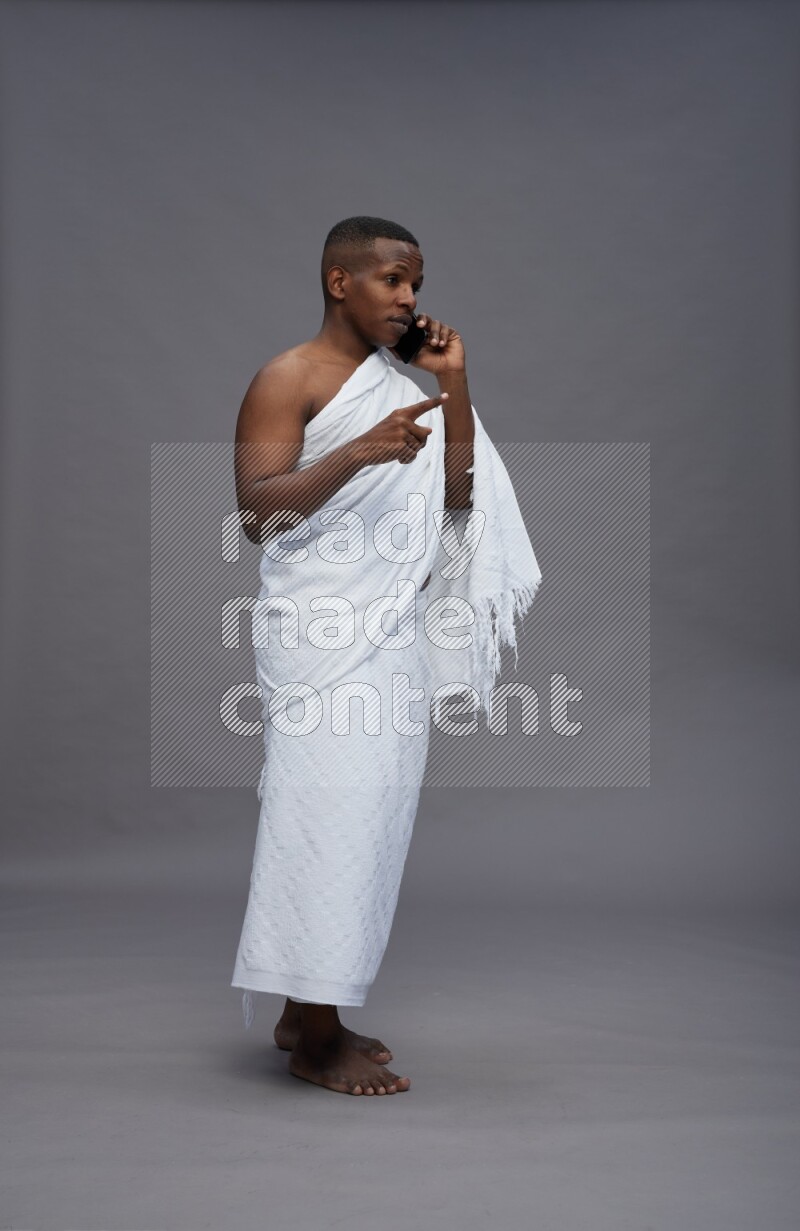 A man wearing Ehram Standing talking on phone on gray background