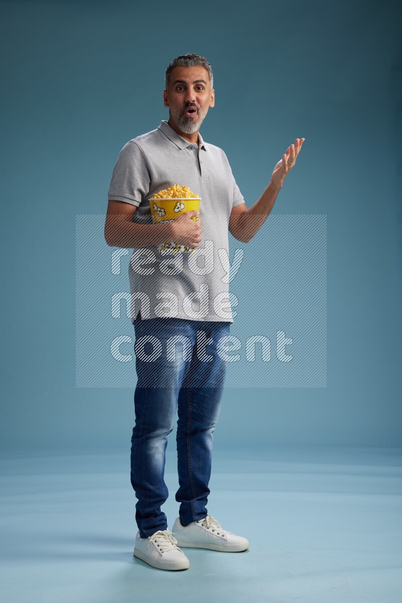 Man Standing eating popcorn on blue background