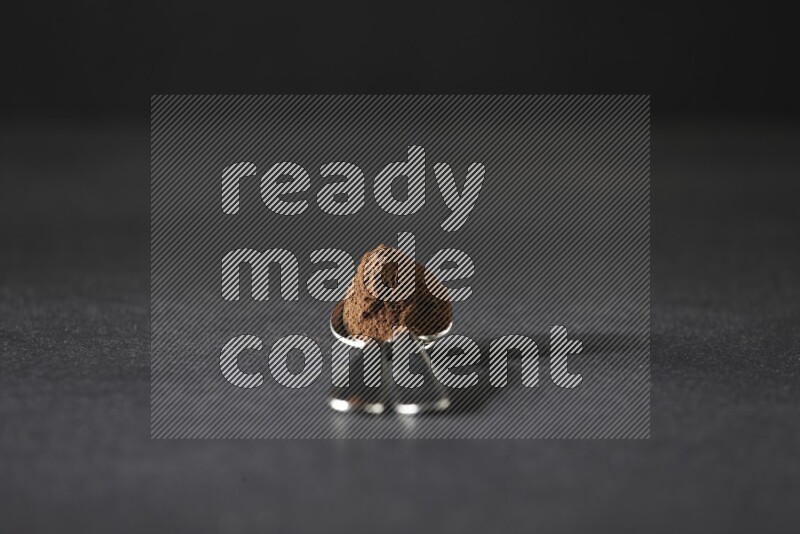 ملعقتان معدنيتان فوق بعضهما البعض ممتلئتان ببودرة القرنفل على أرضية سوداء