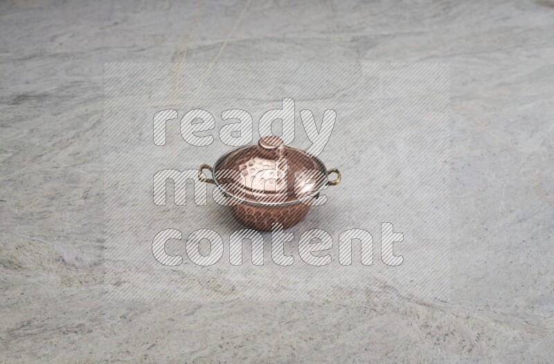 A small copper pot on grey marble background