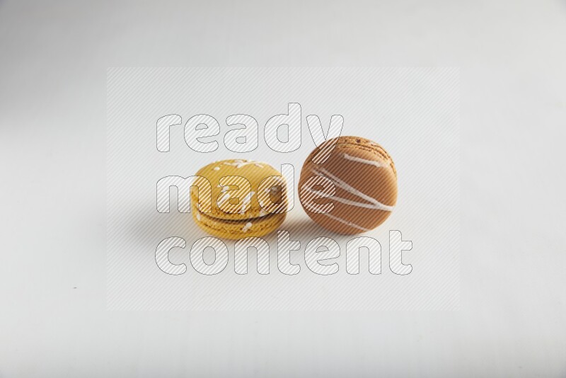 45º Shot of of two assorted Brown Irish Cream, and Yellow Piña Colada macarons on white background