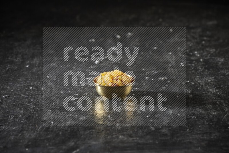 Dried fruits in a metal bowl in a dark setup