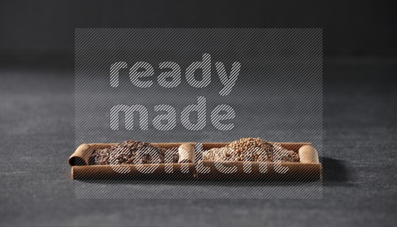 مربعان من أعواد القرفة ممتلئان بحبوب الخردل وبذور الكتان علي خلفية سوداء