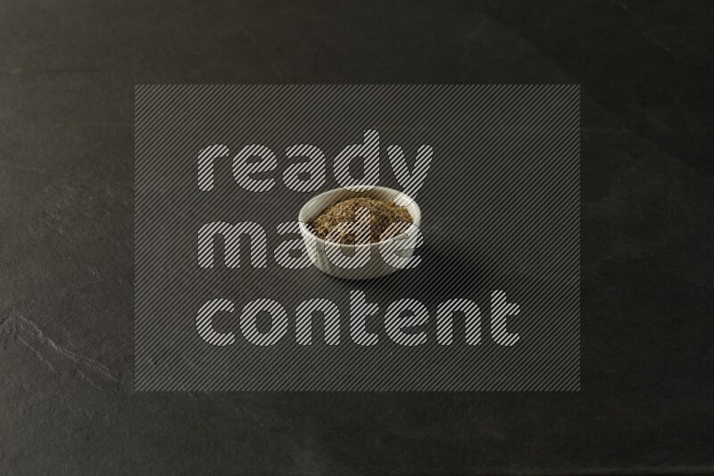 wooden round sauce bowl filled with herbs on grey textured countertop