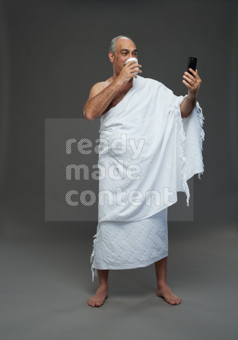 A man wearing Ehram Standing taking selfie on gray background