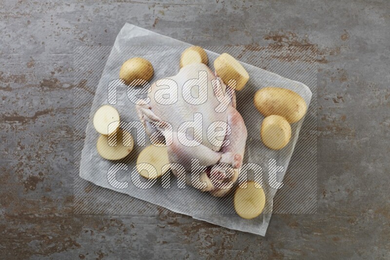 whole raw chicken on a parchment paper direct on a rustic grey background