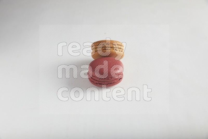 45º Shot of of two assorted Brown Irish Cream, and Red Velvet macarons on white background