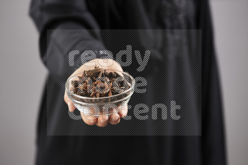 Woman in abaya holding different kinds of spices in different positions