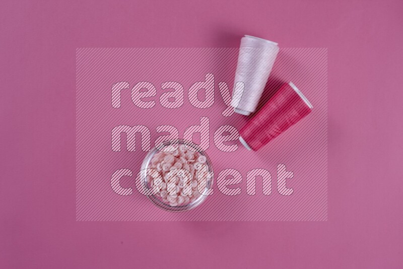 A pink collection of sewing and tailoring tools arranged on a pink background