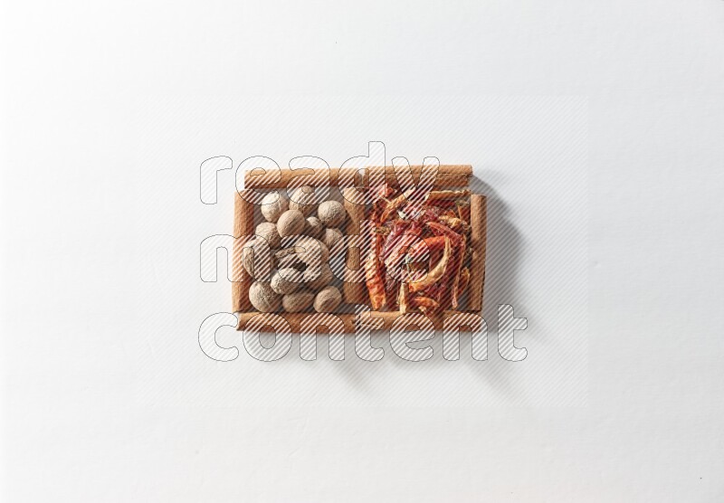 مربعان من أعواد القرفة ممتلئان بالفلفل الحار المجفف وجوزة الطيب علي خلفية بيضاء