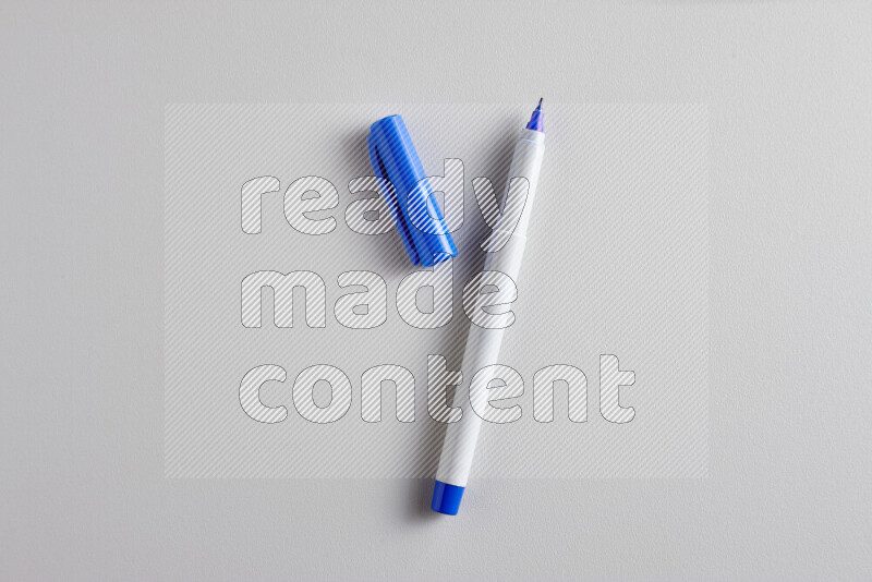 A close-up showing an open single coloring pen with a cap on grey background