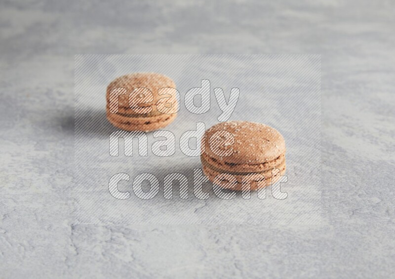 45º Shot of two Brown Hazelnuts macarons  on white  marble background