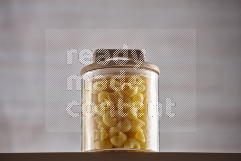 Raw pasta in glass jars on beige background