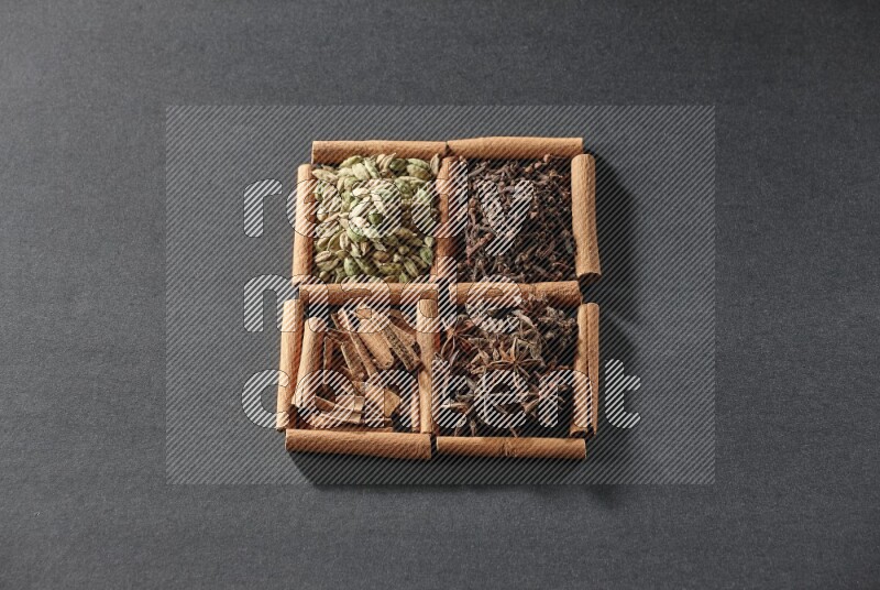 4 squares of cinnamon sticks full of cinnamon, cardamom, cloves and star anise on black flooring