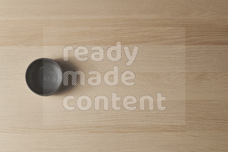 A black pottery bowl on light wooden background