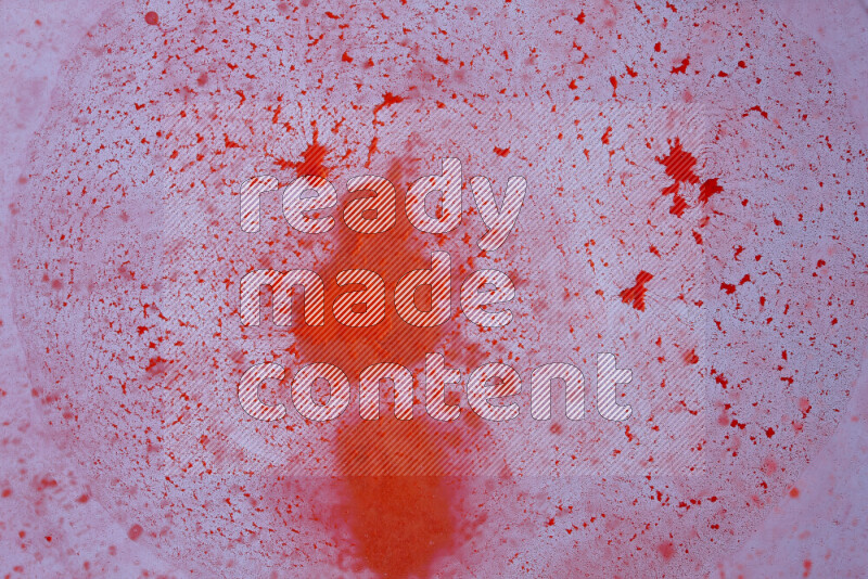 The image captures a dramatic splatter of red paint over a white backdrop
