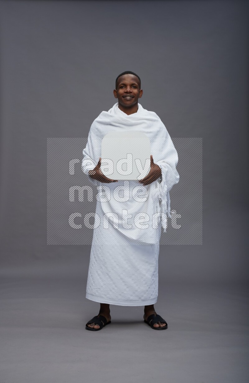 A man wearing Ehram Standing holding social media sign on gray background