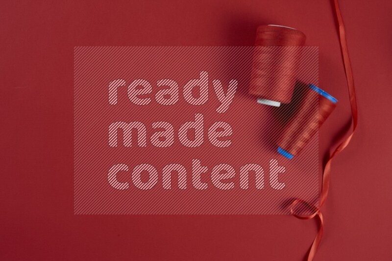 مجموعة من أدوات الخياطة والتفصيل حمراء اللون على خلفية حمراء