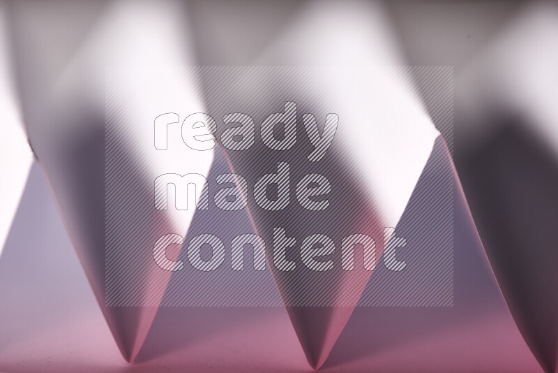 A close-up abstract image showing sharp geometric paper folds in white and pink gradients