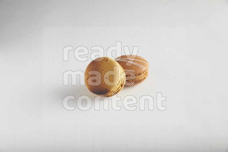 45º Shot of of two assorted Brown Irish Cream, and Yellow Crème Brulée macarons on white background