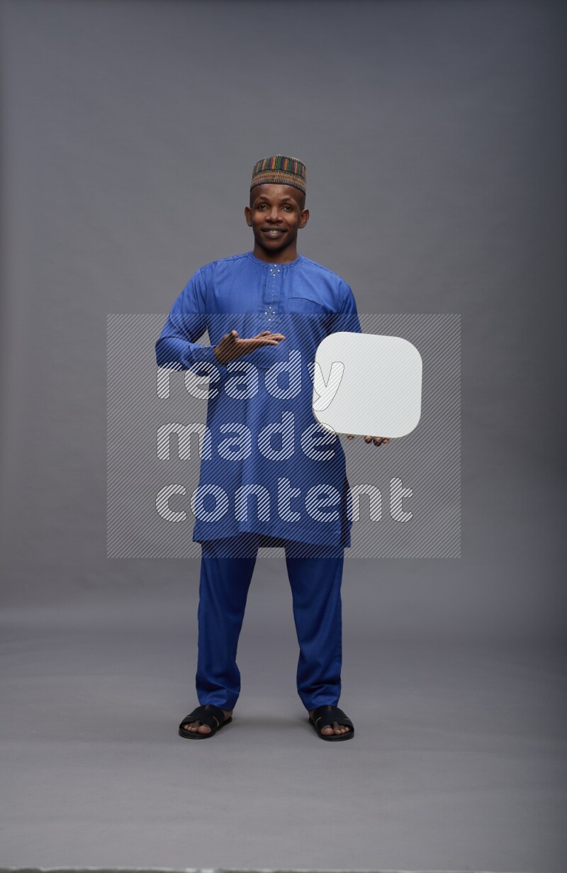 Man wearing Nigerian outfit standing holding social media sign on gray background