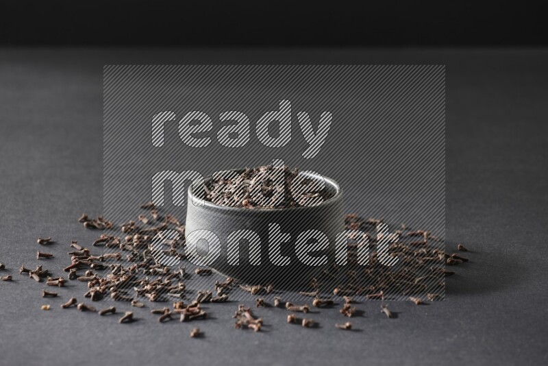 وعاء فخاري أسود ممتلئ بحبوب القرنفل علي خلفية سوداء