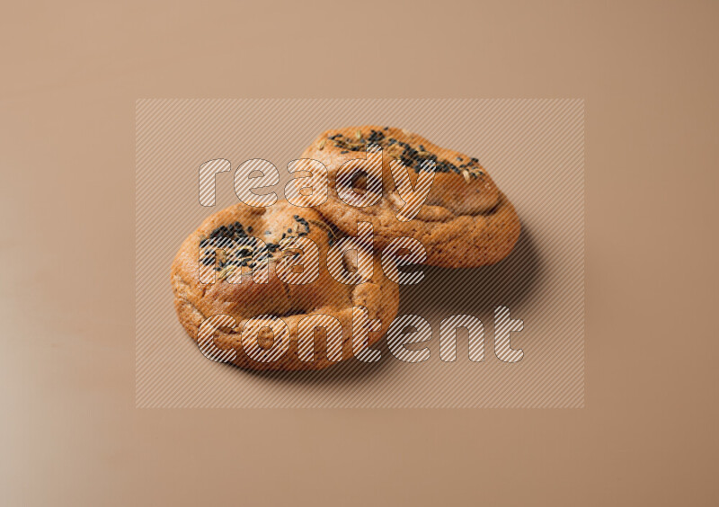 Two chocolate chip cookies on a brown background